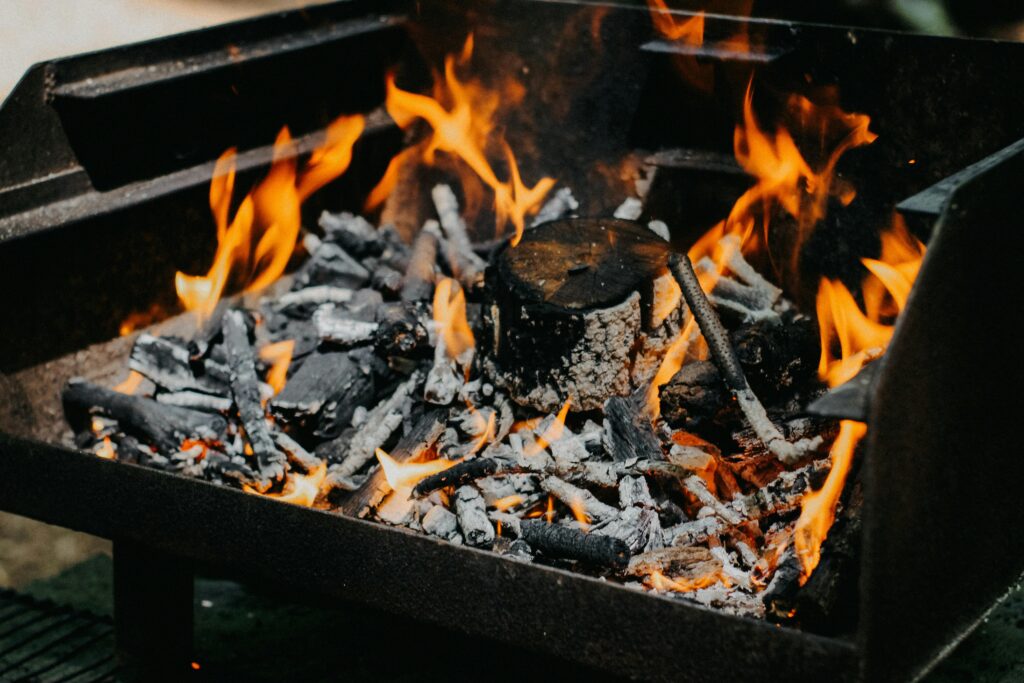 A detailed view of burning charcoal and firewood in a grill, perfect for barbecue enthusiasts.